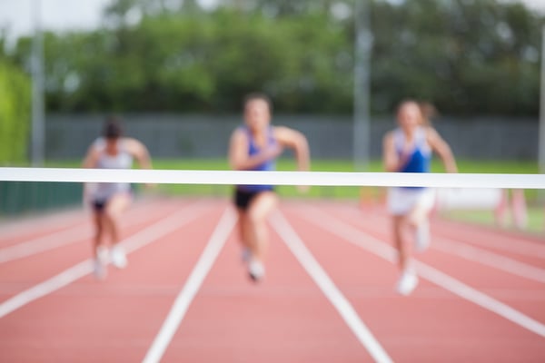 Female athletes running towards finish line on track field-1