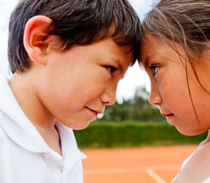 Siblings rivalry - two kids at the tennis court looking competitive
