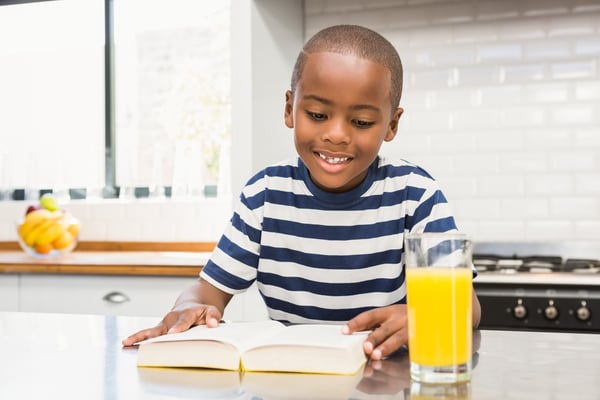 Smiling boy reading a book in the kitchen