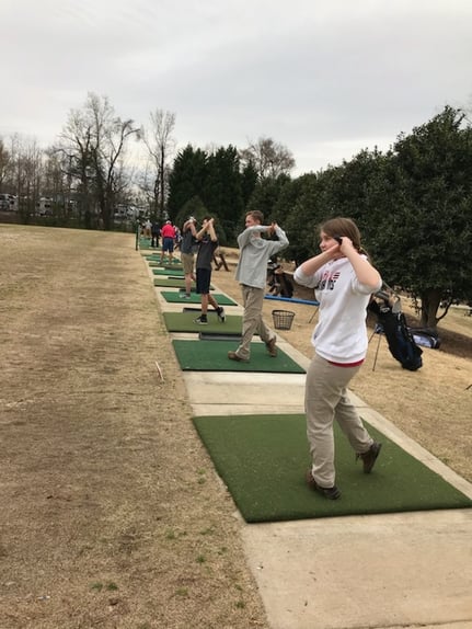 golf team practice swinging golf clubs